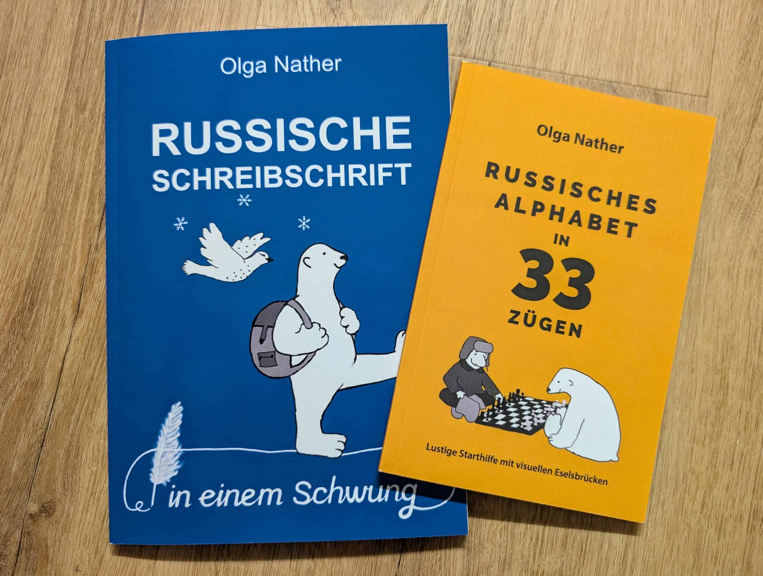 Alt Text: Zwei russische Bücher, "Russische Schreibschrift" und "Russisches Alphabet in 33 Zügen" mit Tier-Illustrationen.